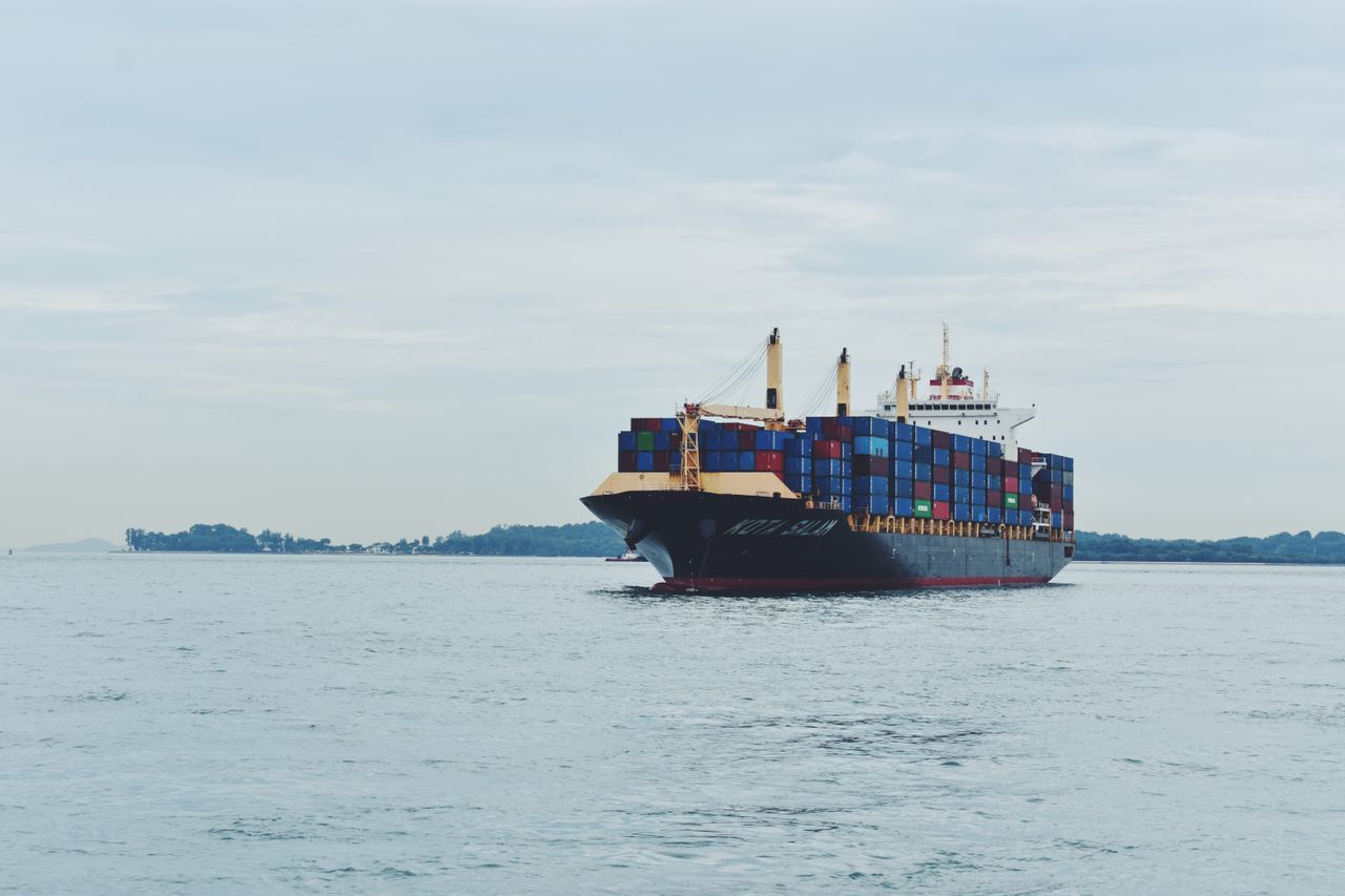 Large cargo ship transporting containers across a calm sea, symbolizing global logistics.